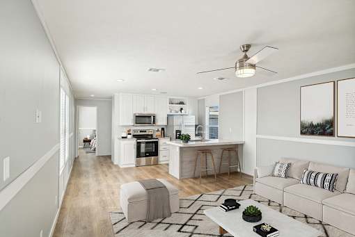 A modern open plan living and kitchen area with a bar stool and a sofa.