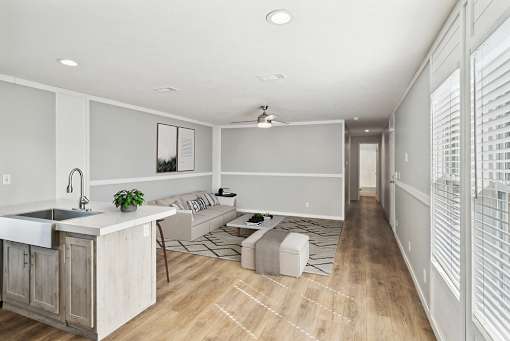 A modern kitchen with a wooden island and a living area with a couch and a rug.