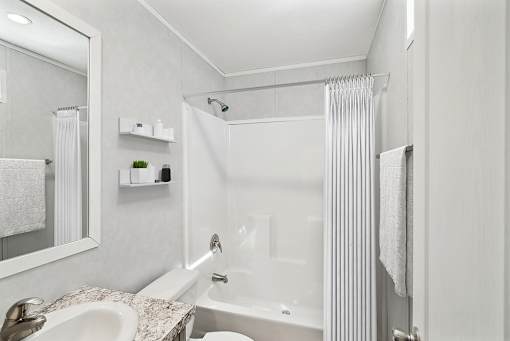 A white bathroom with a sink, mirror, and bathtub.