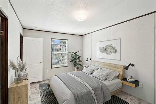 A bedroom with a bed, nightstand, and a plant.