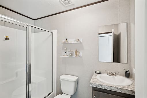 A bathroom with a toilet, sink, mirror, and shower.
