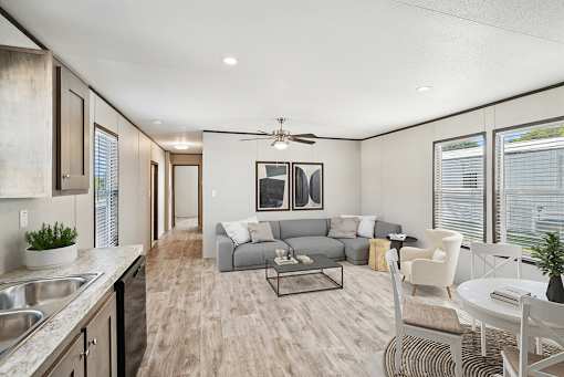 A modern kitchen and living room with a grey sofa and a dining table.