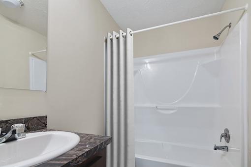 Model bathroom with tub and shower at Candlelight Village Manufactured Home Community in Sauk, IL