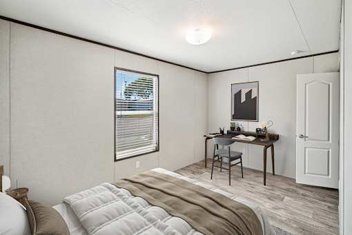A bedroom with a bed, desk, and chair.