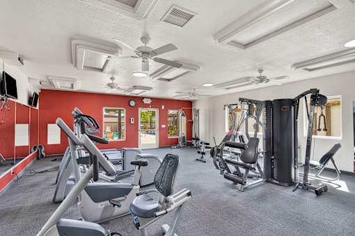 A gym with a variety of equipment including treadmills, weights, and exercise machines.