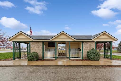 a small brick building with a porch and a flag on the side of it