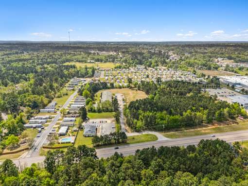 A bird's eye view of a suburban area with a mix of residential and commercial buildings surrounded by greenery.