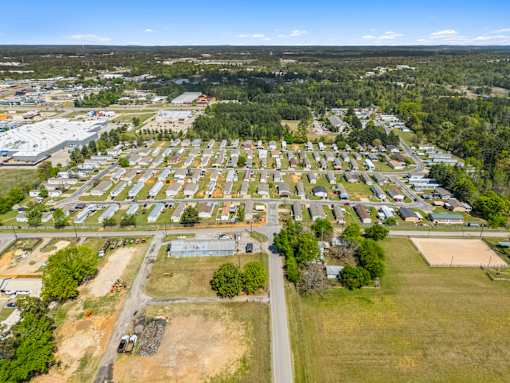 A bird's eye view of a residential area with houses and a large open field.