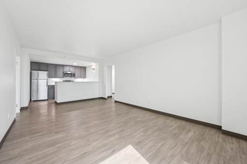 A spacious room with wooden flooring and white walls.