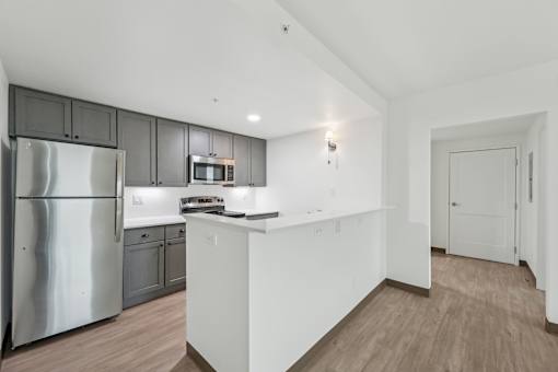 A kitchen with a refrigerator, microwave, and oven.