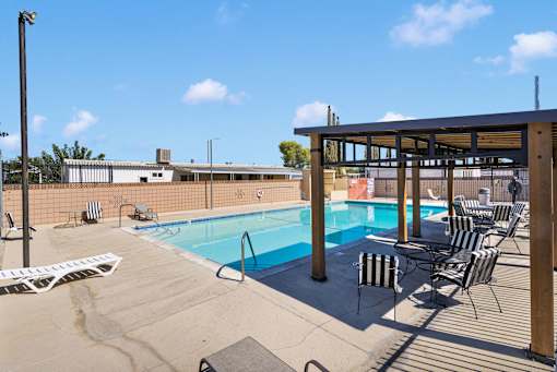 A pool with chairs and a building in the background.