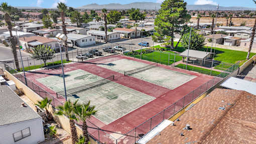 A tennis court surrounded by a fence and a residential area.