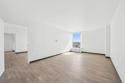 A large empty room with wooden floors and white walls.