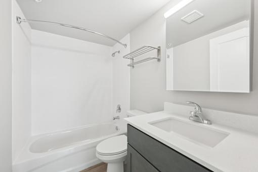 A white bathroom with a toilet, sink, and bathtub.