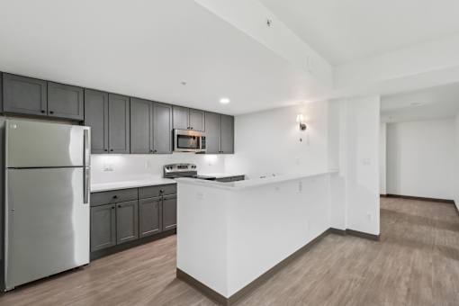 A modern kitchen with a stainless steel refrigerator and wooden flooring.