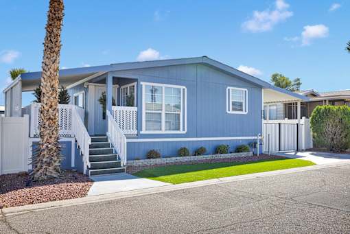 A blue house with a white fence and a palm tree in front.