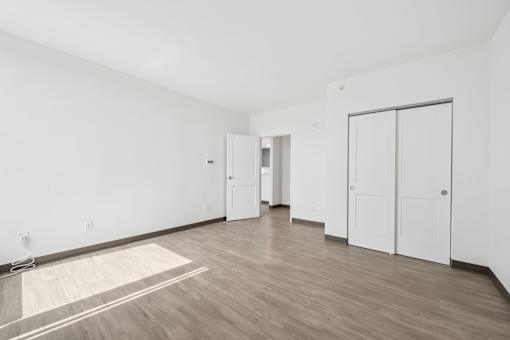 A room with white walls and wooden flooring with a rug on the floor.