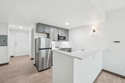 A kitchen with a stainless steel refrigerator and white cabinets.