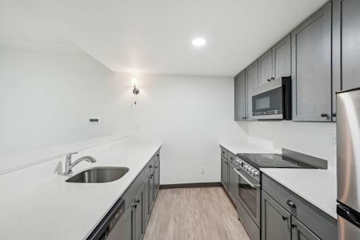 A modern kitchen with stainless steel appliances and wooden flooring.