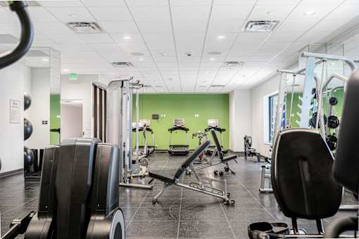 A gym with a variety of equipment including treadmills, weights, and exercise machines.