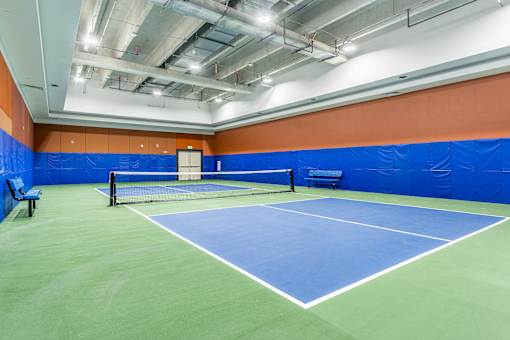 A tennis court with a net and two benches.
