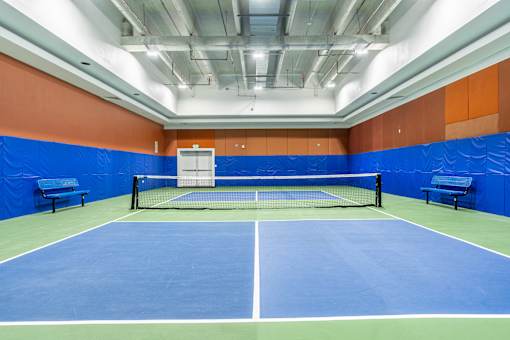 A tennis court with a net and two benches.