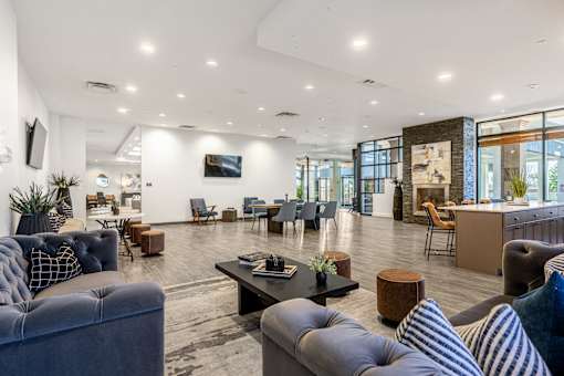 A modern living room with a variety of seating options and a flat screen TV mounted on the wall.