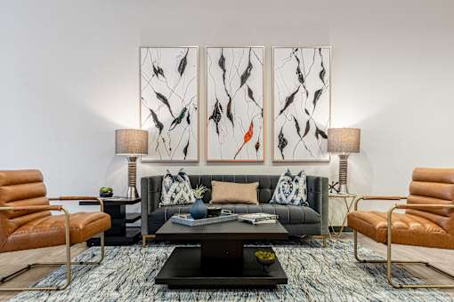 A living room with a black couch, a coffee table, and two chairs.