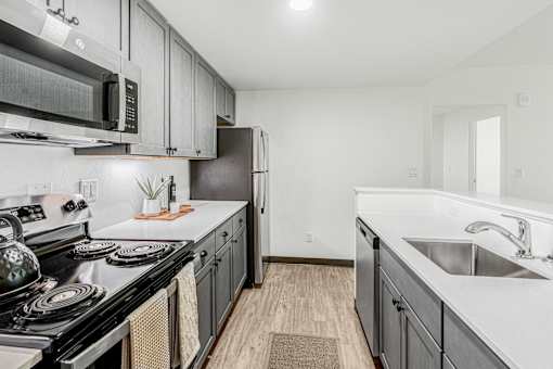 A kitchen with a black stove top oven and a black microwave above it.