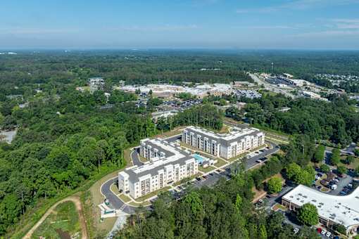 An aerial view of a large building surrounded by trees and a parking lot.