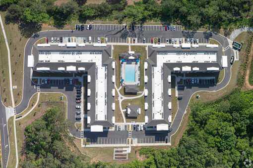 An aerial view of a parking lot and buildings with a pool in the middle.
