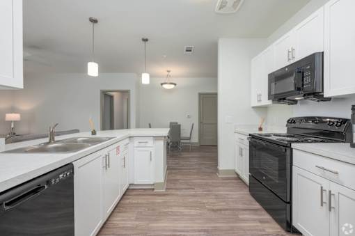 A kitchen with white cabinets and black appliances.