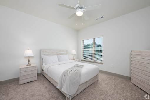 A bedroom with a bed, nightstand, and window.