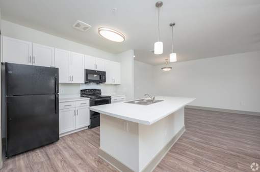 A kitchen with black appliances and white cabinets.