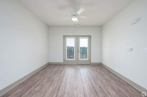 A room with a ceiling fan and a sliding glass door.