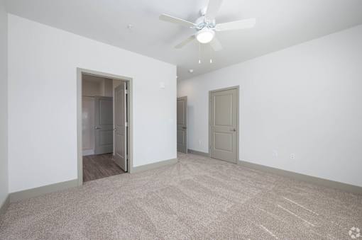 A room with a ceiling fan and carpeted floor.