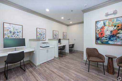 A room with a desk, chairs, and a painting on the wall.