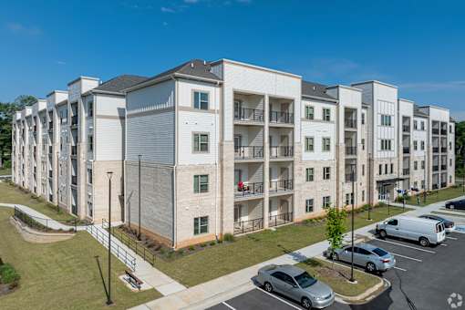 A large apartment complex with a parking lot in front.
