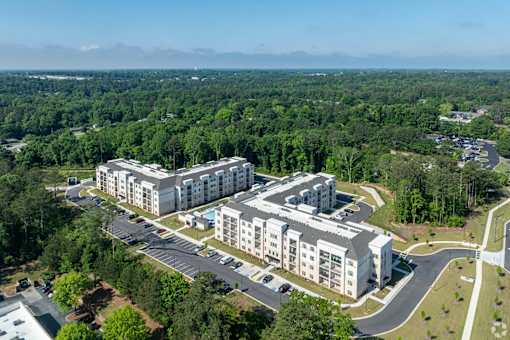 A large white building surrounded by trees and a parking lot.