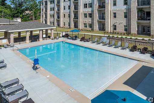 A swimming pool surrounded by lounge chairs and umbrellas.