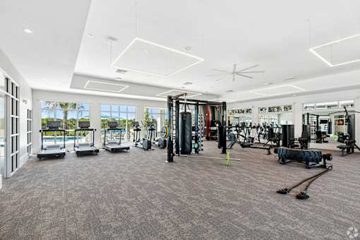 A spacious gym with a variety of equipment and a view of the outdoors through large windows.