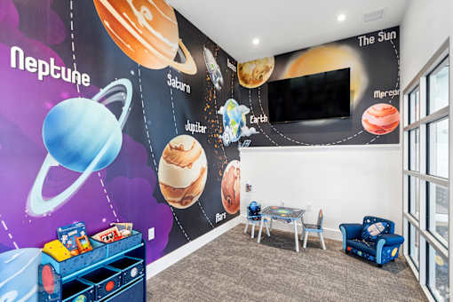 A room with a mural of planets on the wall and a blue sofa.