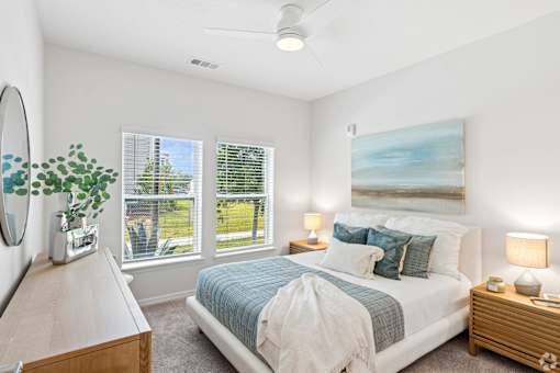 A bedroom with a bed, nightstand, and a painting on the wall.