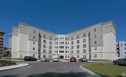 A large white building with a parking lot in front at Arbours at Tumblin Creek ~ Active 55+ Adult Community, Florida