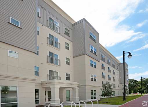 A modern apartment building with a parking lot in front at Arbours at Tumblin Creek ~ Active 55+ Adult Community, Gainesville 32608