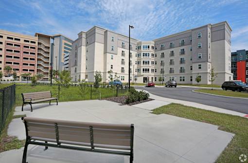 A park area with benches and a building in the background at Arbours at Tumblin Creek ~ Active 55+ Adult Community, 32608