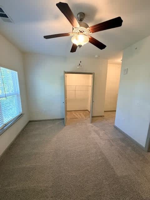 A room with a ceiling fan and carpeted floor.