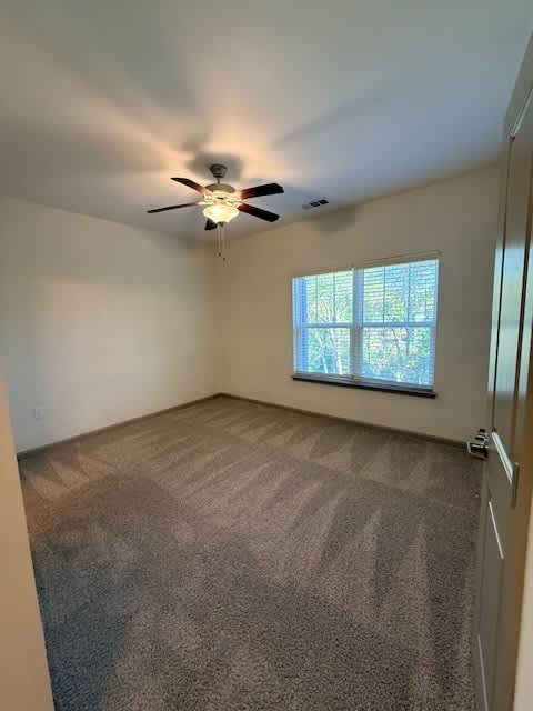 A room with a ceiling fan and carpeted floor.