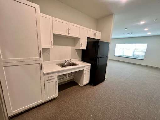 A kitchen with white cabinets and a black refrigerator.at Arbours at Moores Mill, Huntsville