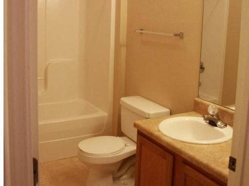 A white toilet sits next to a sink in a bathroom at Arbours at Ensley Apartments, Florida